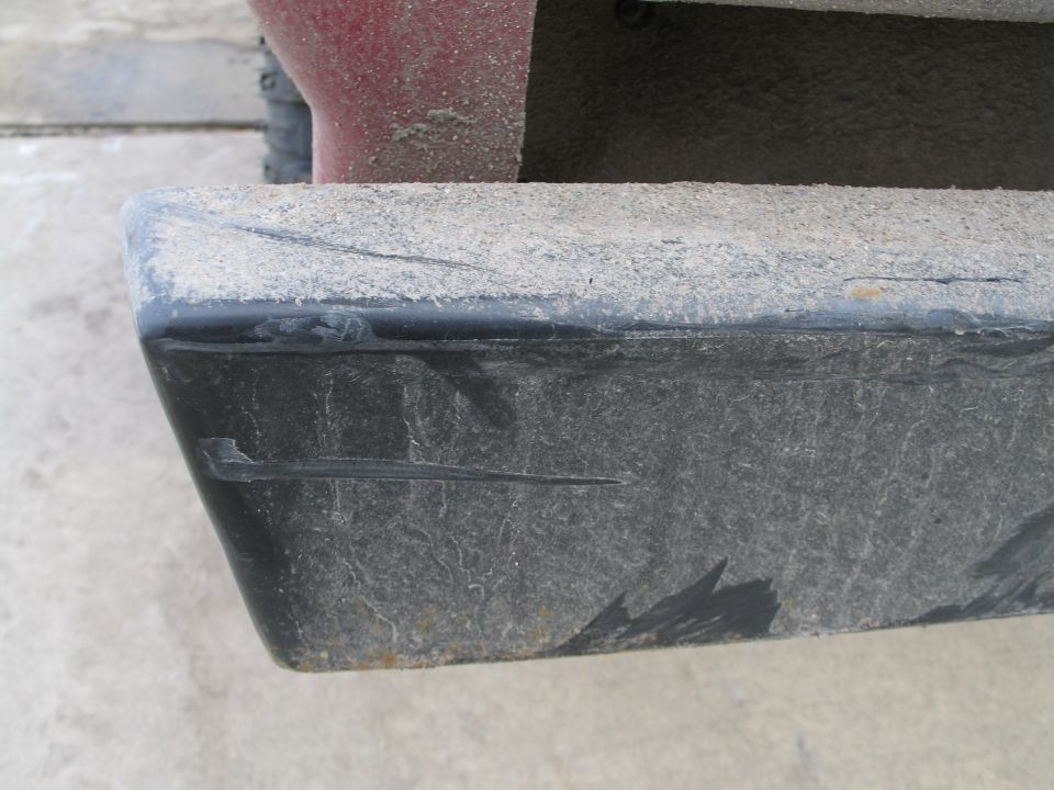 Close-up of a dusty black plastic rear bumper corner with scuff marks
