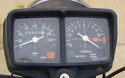 1985 Ford Crown Victoria LTD - Close-up of a motorcycle's speedometer and tachometer gauges, showing mileage and engine speed.