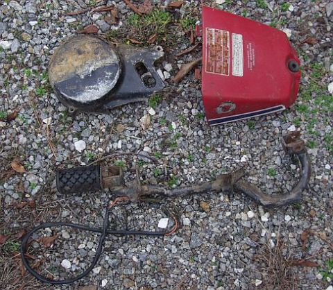 1985 Ford Crown Victoria LTD - Several disassembled motorcycle parts are spread out on a gravel surface.