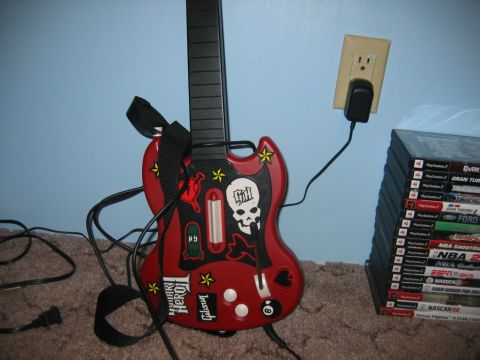 1992 Ford Mustang - A red Guitar Hero controller, decorated with various decals including a skull and the Gibson logo, is plugged into a wall outlet.