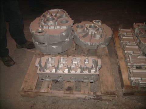 1969 Ford Fairlane - Several cast metal engine components are laid out on wooden pallets in a workshop.
