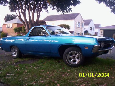 1970 Ford Ranchero - A blue 1970 Ford Ranchero is seen from the side, parked in front of houses.