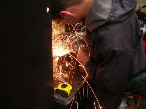1979 Ford Bronco - Grinding metal sparks fly as a person works on a project. A tape measure sits nearby.