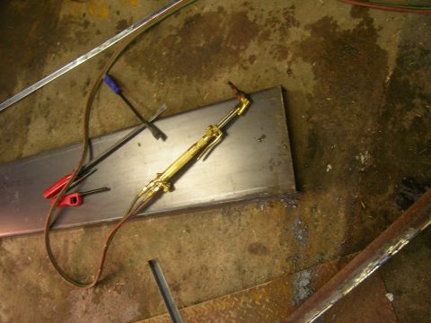1979 Ford Bronco - A welding torch and metal plate are on a workshop floor, with tools scattered around.