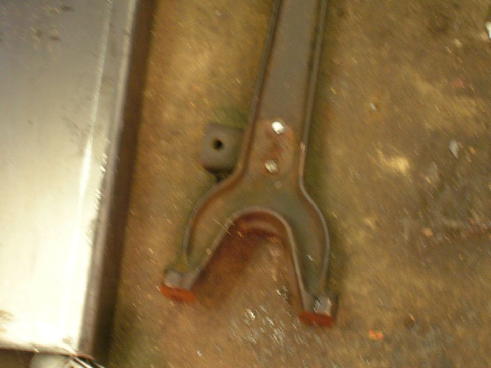 Rusty metal automotive part with orange rubber tips on a dirty surface