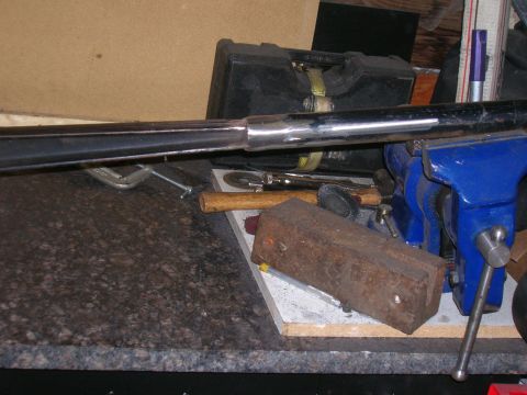 1979 Ford Bronco - A chrome pipe is clamped in a vise on a workbench, surrounded by various tools and materials.