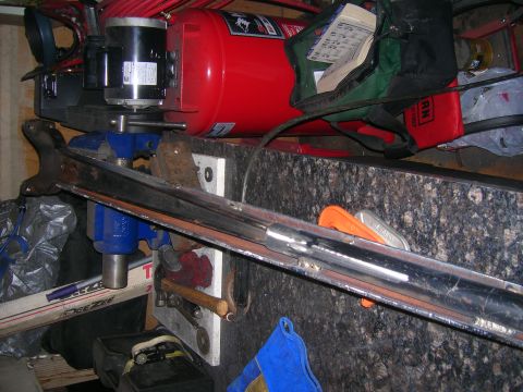 1979 Ford Bronco - A chrome-plated part is secured in a vise, with an air compressor and motor visible behind it.
