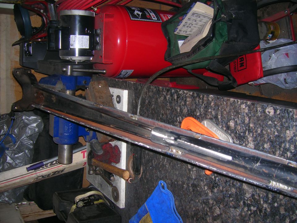 Chrome-plated part held in a blue vise, with a red air compressor and motor in the background