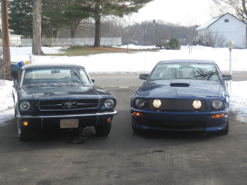 1965 Ford Mustang parked next to a modern blue Ford Mustang