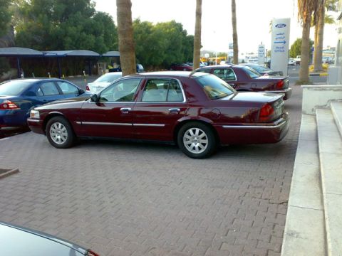 1999 Mercury Grand Marquis - A maroon sedan is parked on a brick surface, with another similar vehicle visible behind it.