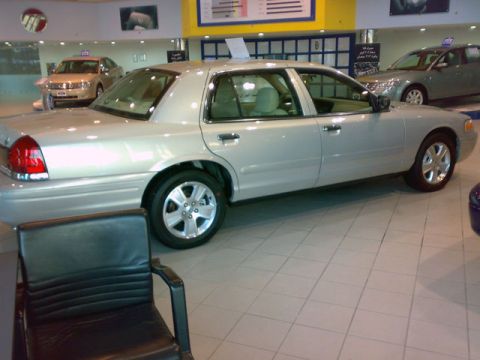 1999 Mercury Grand Marquis - A silver sedan is parked in a showroom, with another car visible in the background.