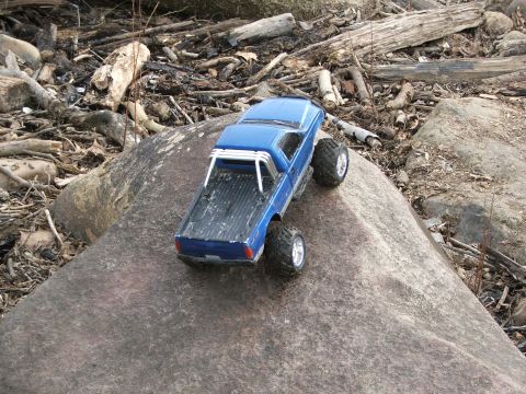 1996 Ford Bronco - A remote-controlled pickup truck navigates a rocky terrain with debris in the background.