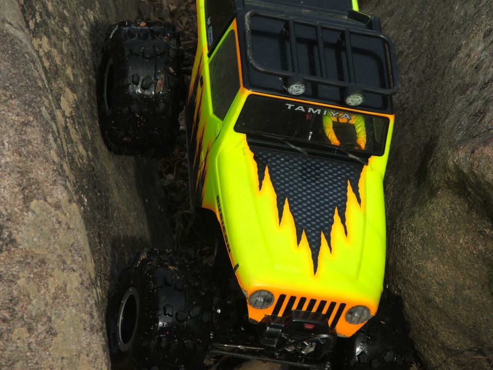 Yellow RC car with flame decals and Tamiya logo on rocks