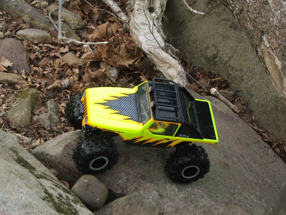 Yellow remote control rock crawler with black flame decals on rocks