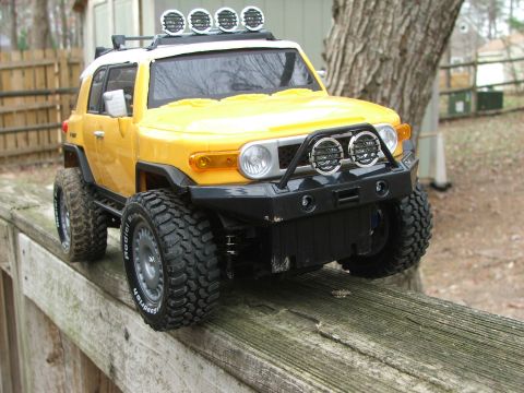 1996 Ford Bronco - A remote-controlled toy SUV with aggressive tires and auxiliary lights is positioned on a weathered wooden surface.