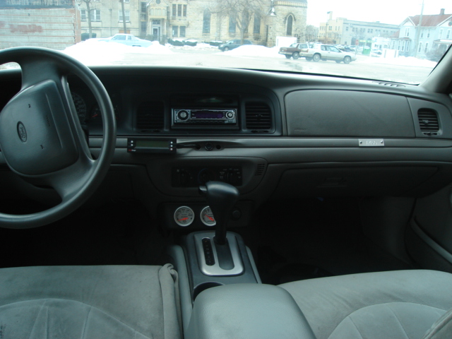 2000 Ford Crown Victoria interior with gray seats, dashboard, steering wheel, and aftermarket radio
