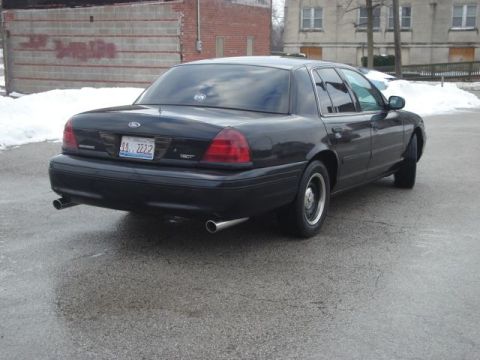 2000 Ford Crown Victoria - A black 2000 Ford Crown Victoria sedan is viewed from the rear, showing its dual exhaust and license plate.