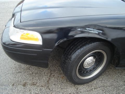 2000 Ford Crown Victoria - Front driver's side fender and wheel of a dark 2000 Ford Crown Victoria showing damage.