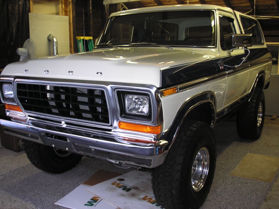 Front view of a lifted white and black Ford Bronco in a garage