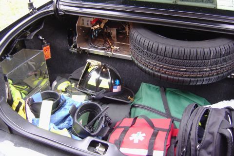 2003 Ford Crown Victoria - Emergency gear, including a helmet and medical supplies, is organized in the trunk of a vehicle.