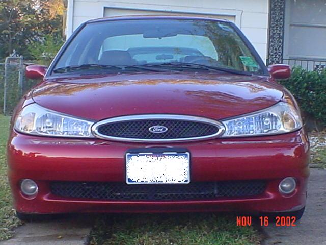 Front view of a dark red Ford sedan parked by a garage