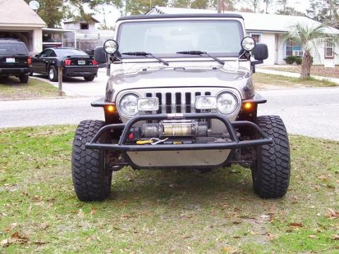 2004 Jeep TJ - Silver Jeep Wrangler with winch and aftermarket bumper parked on grass.