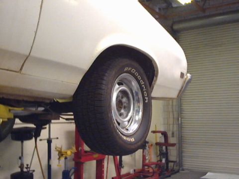 1969 Chevrolet Nova - A white 1969 Chevrolet Nova is shown on a lift, revealing its rear wheel and side panel.