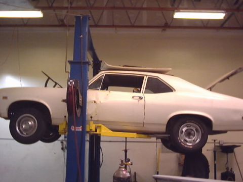 1969 Chevrolet Nova - White coupe on a car lift in a garage, rear trunk is open. Appears to be a 1970s model.