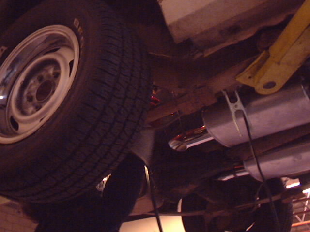 Underside view showing steel wheel, tire and chrome muffler on a lifted car