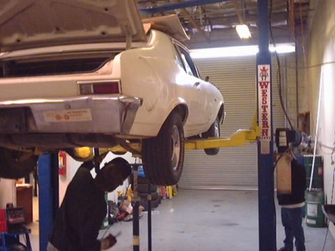 1969 Chevrolet Nova - A white sedan is being worked on while on a car lift in a garage.