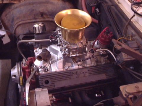 1969 Chevrolet Nova - Engine bay detail a carburetor and a gold air intake horn.