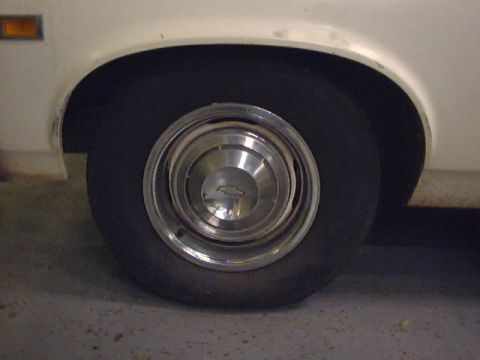 1969 Chevrolet Nova - Close-up of a white 1969 Chevrolet Nova's rear wheel and fender assembly, showing a chrome hubcap with the Chevrolet logo.