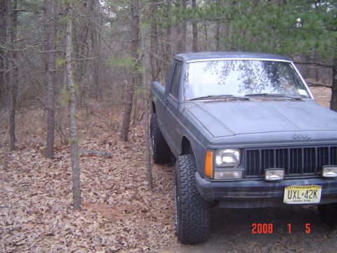 1988 Jeep Comanche - This 1988 Jeep Comanche pickup truck is parked in a wooded area with fallen leaves on the ground.