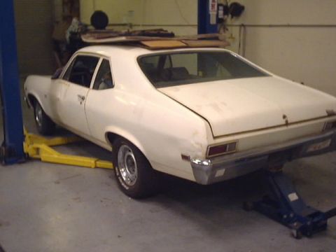 1969 Chevrolet Nova - This white 1969 Chevrolet Nova is being worked on in a garage, supported by a lift and a floor jack.