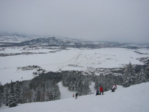 2006 BMW 5 Series - A wide view of a snow-covered valley and mountains, with several skiers on the slope in the foreground.