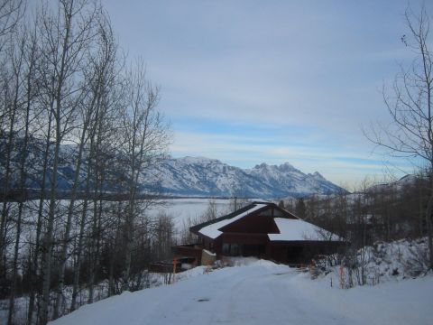 2006 BMW 5 Series - A house sits on a snow-covered hill with mountains in the background.