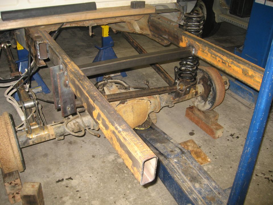 Truck frame and suspension with added metal bracing, viewed from rear