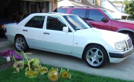 2003 Ford Crown Victoria - A white Mercedes-Benz sedan is parked in front of a red SUV.