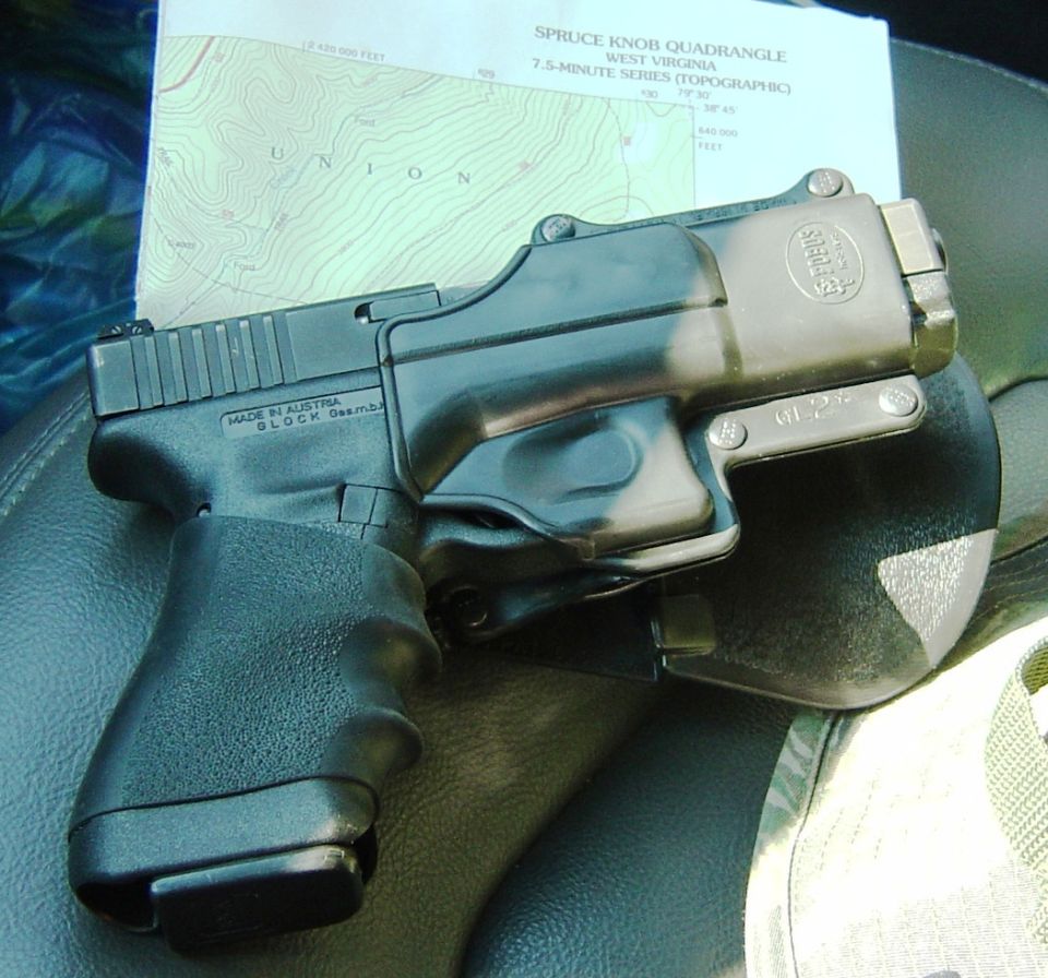 Black Glock pistol in a Fobus holster lying on a seat beside a West Virginia topographic map