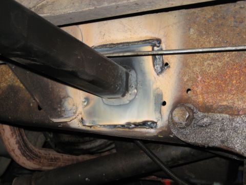 1990 Ford Bronco - Close-up view of a vehicle's undercarriage, focusing on a welded frame section and attached pipe.