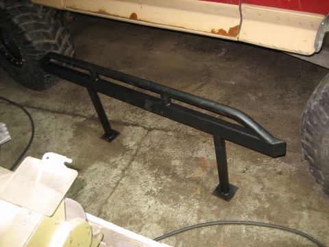 1990 Ford Bronco - Rock sliders are installed on the side of a vehicle, visible next to large tires.