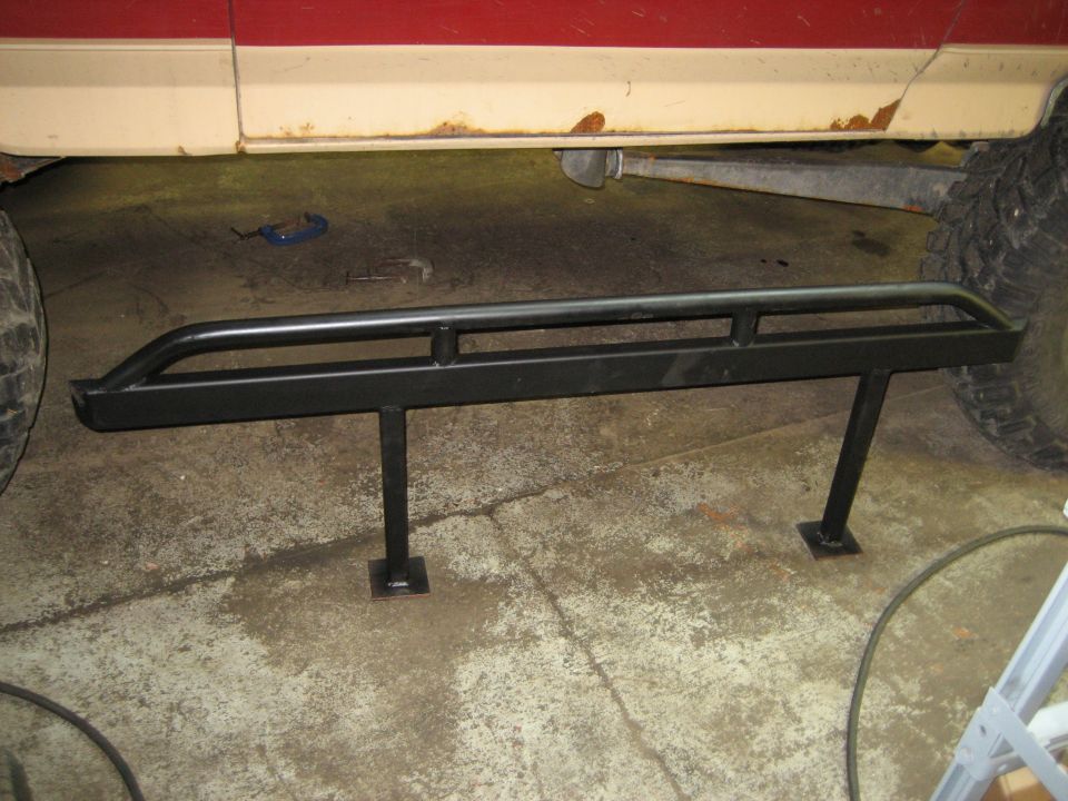 black rock sliders mounted under the side of a red and tan vehicle