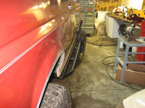 1990 Ford Bronco - Side view of a red 1990 Ford Bronco, highlighting its rock sliders and fender detail.