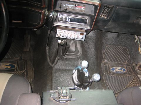 1990 Ford Bronco - The interior of the vehicle features a CB radio mounted below the stereo and two gear shifters.