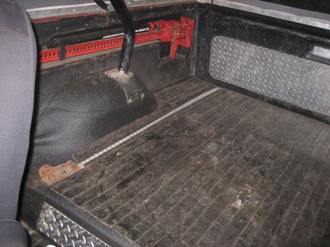 1990 Ford Bronco - The cargo area of a vehicle features a red hi-lift jack and diamond plate accents on the interior panels.