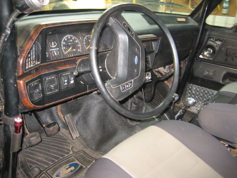 1990 Ford Bronco - The interior of a truck features a wood-grain trim dashboard with various switches and gauges.