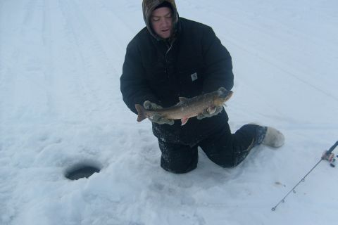 1979 Chevrolet Blazer - A man proudly displays a freshly caught fish while ice fishing, with a fishing rod visible in the snowy landscape.