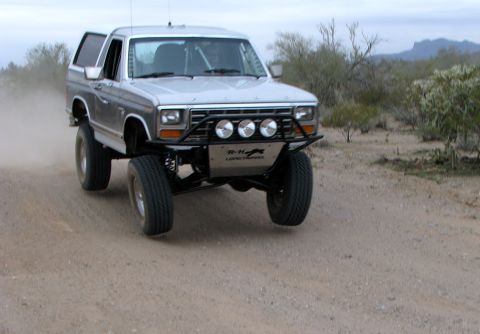 1980 Ford Bronco - A modified 1980 Ford Bronco navigates a dusty desert trail, its off-road capabilities.