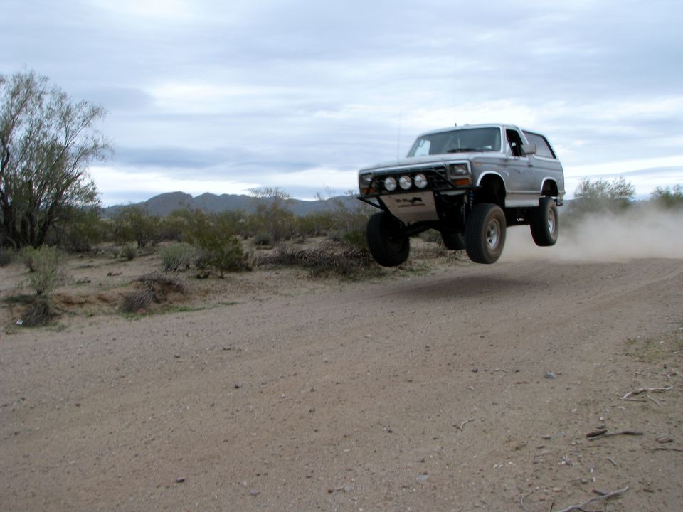 Silver 1980 Ford Bronco jumping in desert