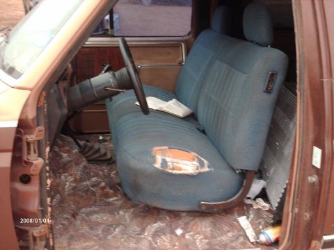 1990 Ford F-150 - The interior of a 1990 Ford F-150 reveals a worn blue bench seat and the driver's side dashboard area.